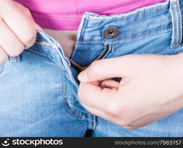 female hand unzips jeans zipper close up