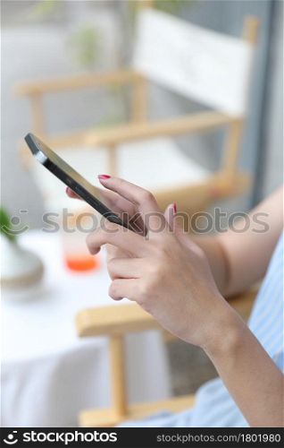 Female hand with smartphone trading stocks online in coffee shop Business concept