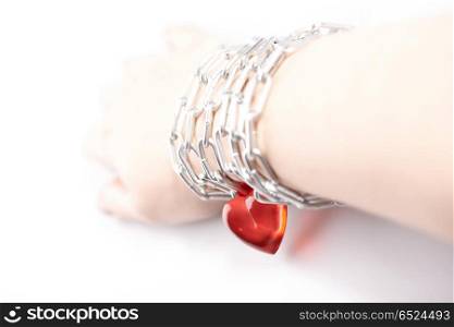 Female hand wound by a chain with heart. Unusual love