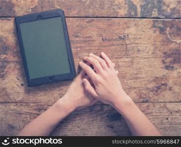 Female hands and a tablet computer on a wooden table