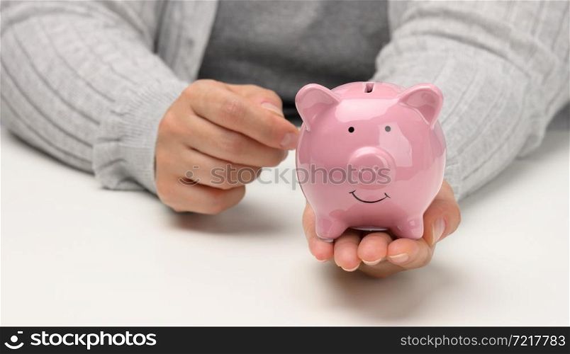 female hands are holding a pink ceramic piggy bank. Accumulation concept, budget control
