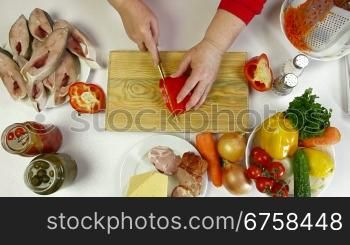 Female hands cooking ingredients for baked fish - chopping bell pepper. Shoot from above