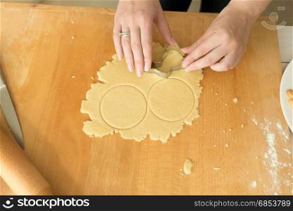 Female hands cutting dough for cookies