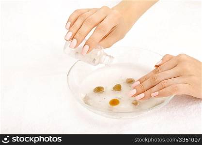 Female hands fill salt in the cosmetic bath, isolated on a white background