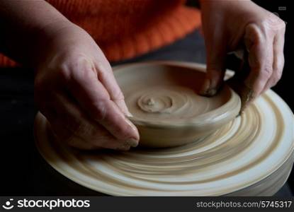 Female hands forming clay pot on the pottery wheel
