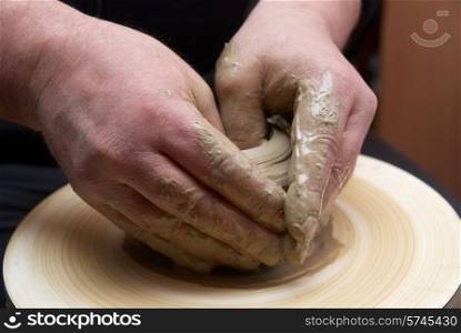 Female hands forming clay pot on the pottery wheel