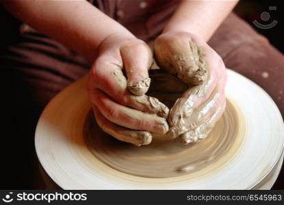 Female hands forming clay pot on the pottery wheel . Hands forming clay pot