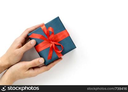 Female hands giving a Blue Gift box with red ribbon on white background. Preesent. Top view. Copyspace.. Female hands giving a Blue Gift box with red ribbon on white background. Top view. Copyspace