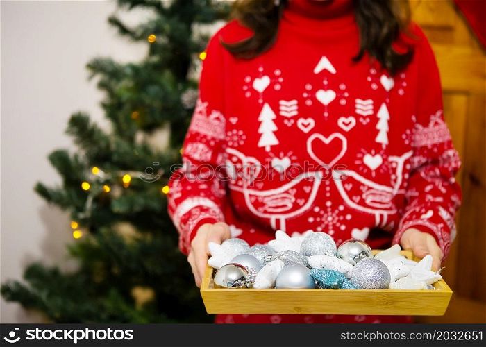Female hands hold a tray in which there are a lot of Christmas tree toys. Christmas tree decoration process. New Year Christmas. 2022 year of the tiger. Female hands hold a tray in which there are a lot of Christmas tree toys. Christmas tree decoration process. New Year Christmas. 2022 year of the tiger.