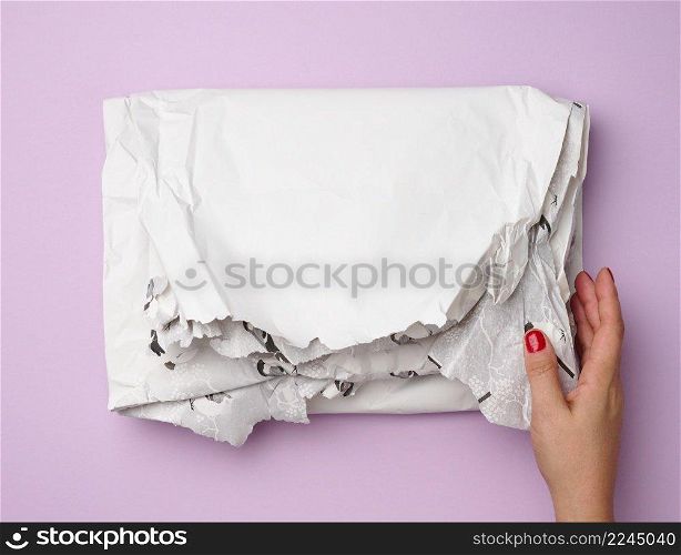 female hands hold crumpled white paper on purple background, top view