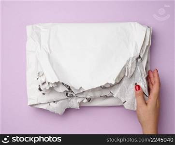 female hands hold crumpled white paper on purple background, top view