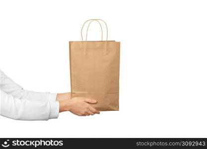 Female hands hold large gift bag made of brown craft paper on white background. Gift, present or e-shopping concept. Female hands hold large gift bag made of brown craft paper on white background. Gift, present or e-shopping concept.
