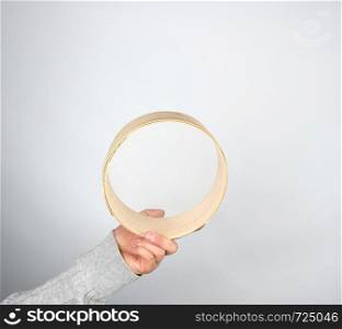 female hands hold round wooden sieve for flour, gray background