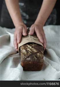 Female hands hold rye bread on dark background