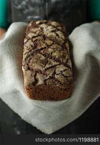 Female hands hold rye bread on dark background