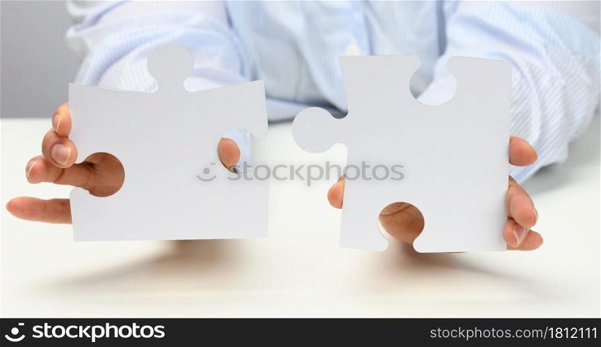 female hands hold white large paper puzzles. Solution concept, strategy and goal achievement