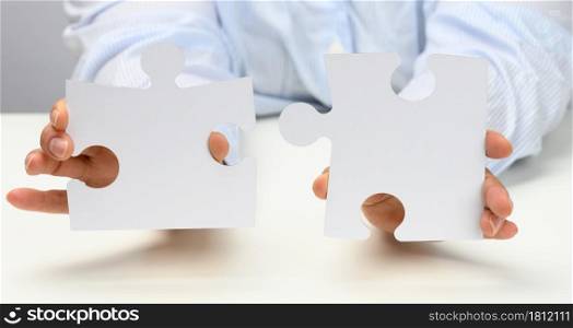 female hands hold white large paper puzzles. Solution concept, strategy and goal achievement