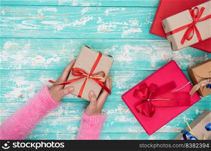 female hands holding a small box with a gift among winter festive decorations on a white table top view.  Flat lay composition for birthday, christmas or wedding.