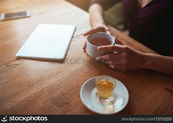 Female hands holding cup top view on wooden background. Female hands holding cup top view