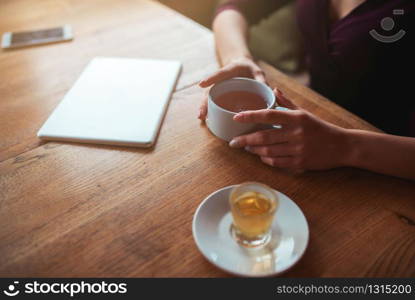 Female hands holding cup top view on wooden background. Female hands holding cup top view