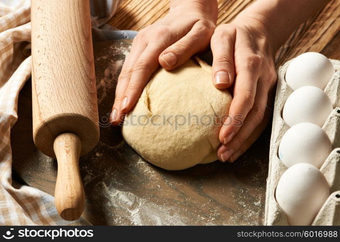 Female hands kneading dough on wooden table