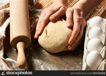 Female hands kneading dough on wooden table