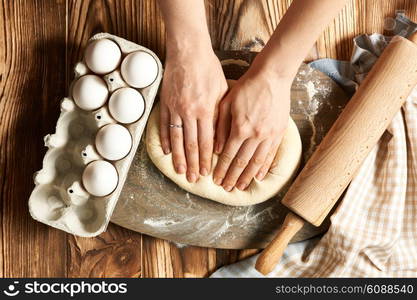 Female hands kneading dough on wooden table