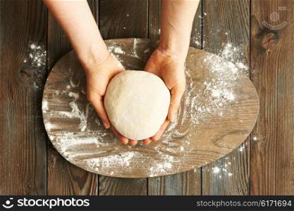 Female hands kneading dough on wooden table