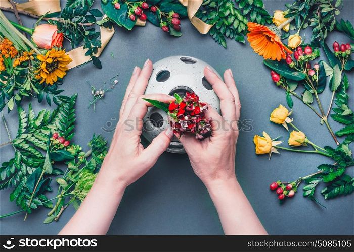 Female hands make Creative autumn floral arrangement with various flowers and plant leaves arrangement on blue table , top view. Florist workplace. Greeting and holiday, concept