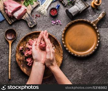 Female hands making meat balls on kitchen table background with meat, force meat , meat grinder and spoon, top view. Cooking,recipes and eating concept