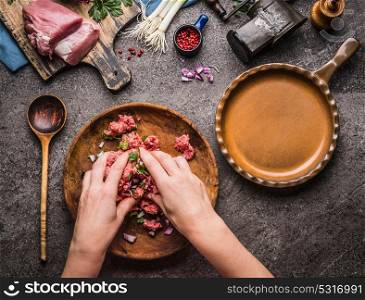 Female hands making minced meat stuffing on kitchen table background with meat, force meat , meat grinder and spoon, top view. Cooking,recipes and eating concept