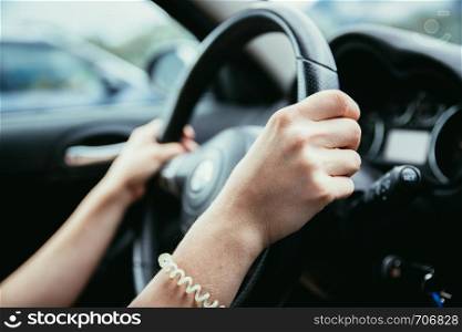 Female hands on a sports car steering wheel, car interior