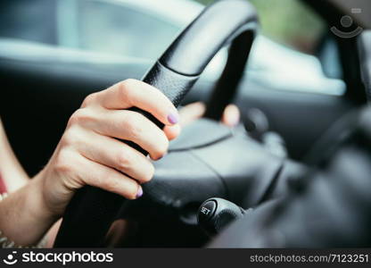 Female hands on a sports car steering wheel, car interior