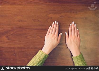 Female hands on wooden background. View to female hands on table from the top.