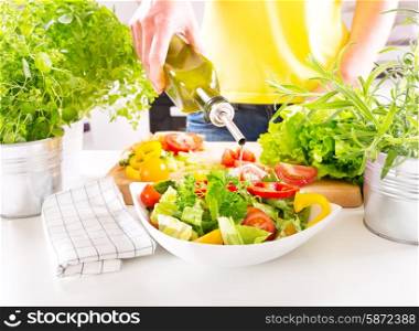 female hands pouring oil from bottle into the bowl of salad in the kitchen