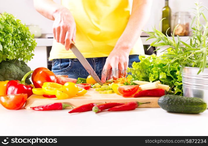 Female hands preparing vegetable salad on wooden board in the kitchen