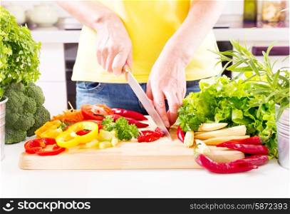 Female hands preparing vegetable salad on wooden board in the kitchen