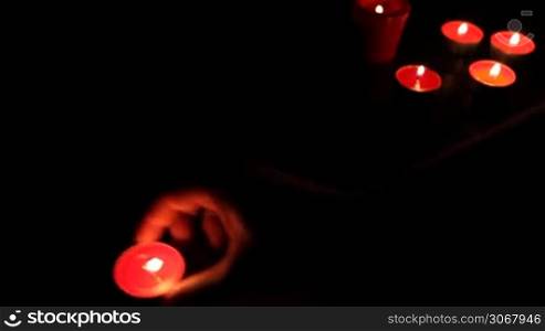 female hands put red candles with fusil wax in semicircle, small lights