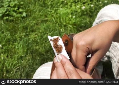 Female hands that put tobacco on cigarette paper