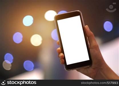 Female hands using modern smartphone with blank screen for design or logo on the background of the lights of a night city.