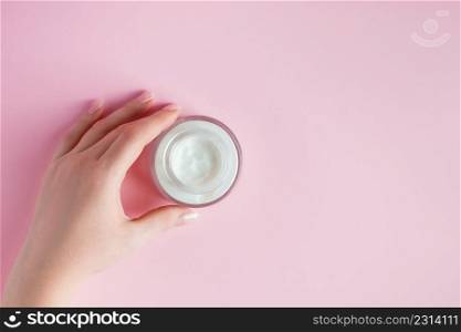 Female hands with a bottle of cream on a pink background. Spa and body care concept. Image for advertising.. Female hands with a bottle of cream on pink background. Spa and body care concept. Image for advertising.