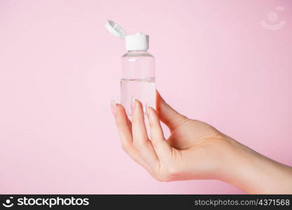 Female hands with a bottle of cream on a pink background. Spa and body care concept. Image for advertising.. Female hands with a bottle of cream on pink background. Spa and body care concept. Image for advertising.