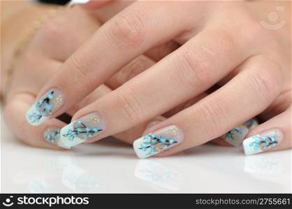 Female hands with manicure close up. Drawing of a branch with blue flowers.With reflection