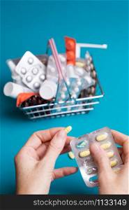 female hands with pills on the background consumer basket products with medicines