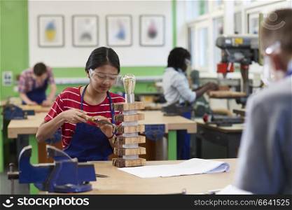 Female High School Student Building Lamp In Woodwork Lesson
