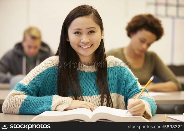 Female High School Student Studying At Desk In Classroom
