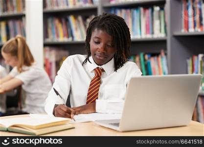 Female High School Student Wearing Uniform Working At Laptop In Library