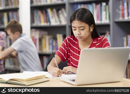 Female High School Student Working At Laptop In Library