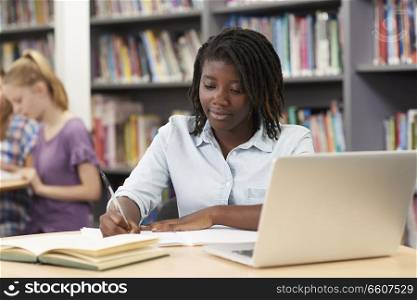 Female High School Student Working At Laptop In Library