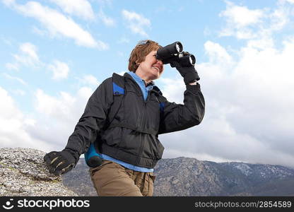 Female hiker using binoculars in mountains